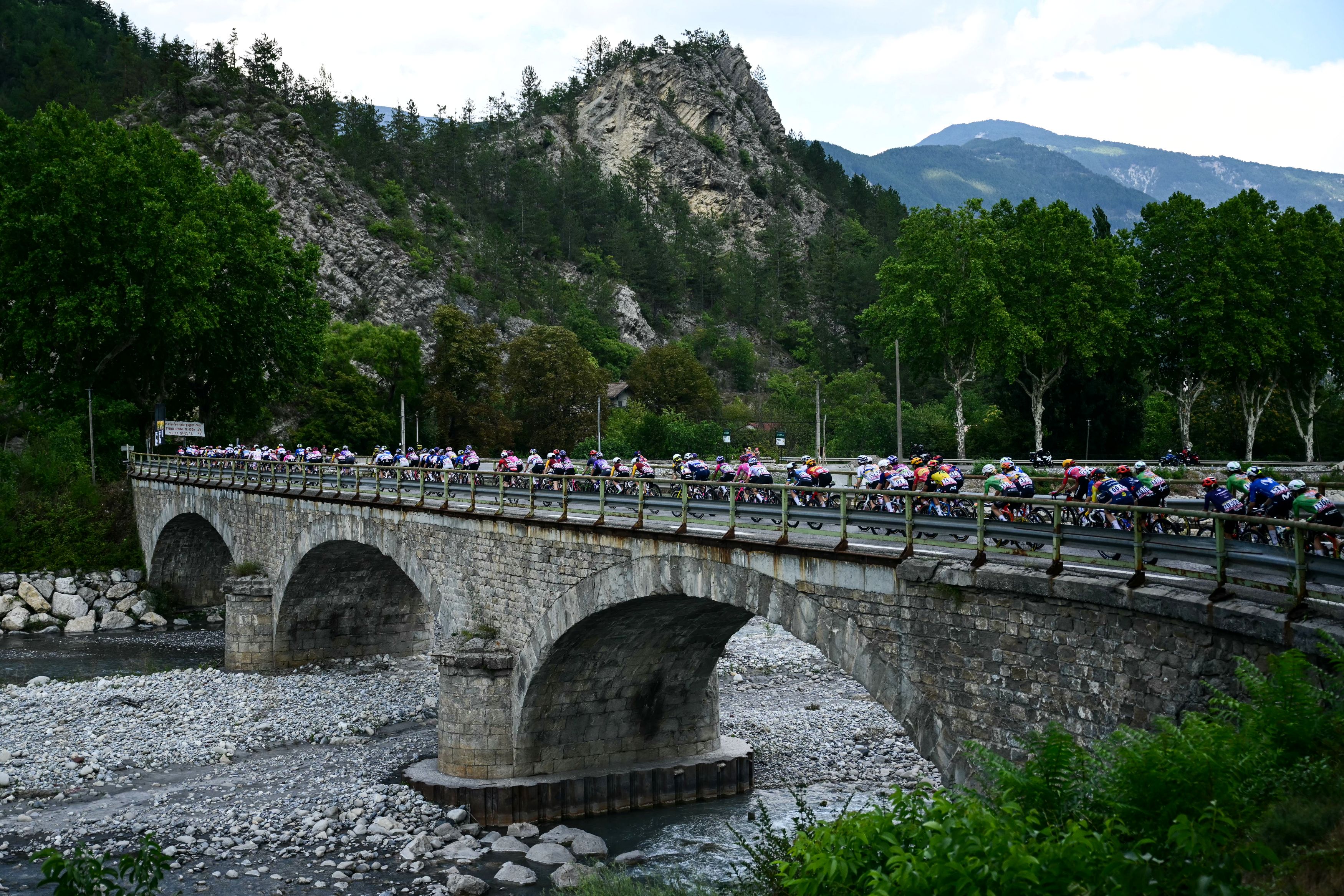 The pack rides on a bridge over the Var River during the 8th (out of 9) stage of the fifth edition of the Women's Tour de France cycling race, 171.9 km from Sisteron to Nice, in Puget-Theniers, southeastern France on August 8, 2026. (Photo by NICOLAS TUCAT / AFP via Getty Images)