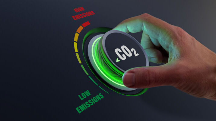 Lower CO2 emissions to limit global warming and climate change. Concept with manager hand turning knob to reduce levels of CO2. New technology to decarbonize industry, energy and transport Hand turning dial marked CO2 to