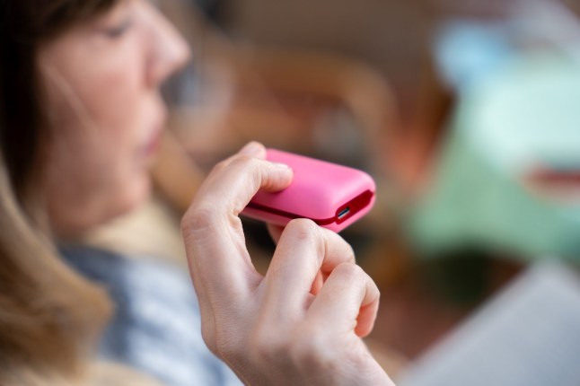 Woman using pink electronic cigarette vape.