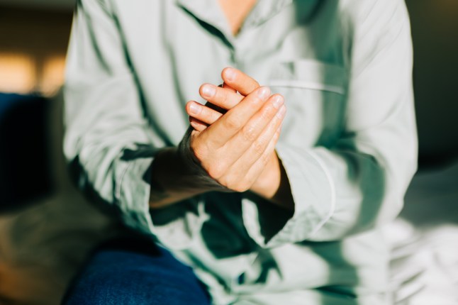 A close-up of a woman's hands as she rubs them together, applying hand cream.