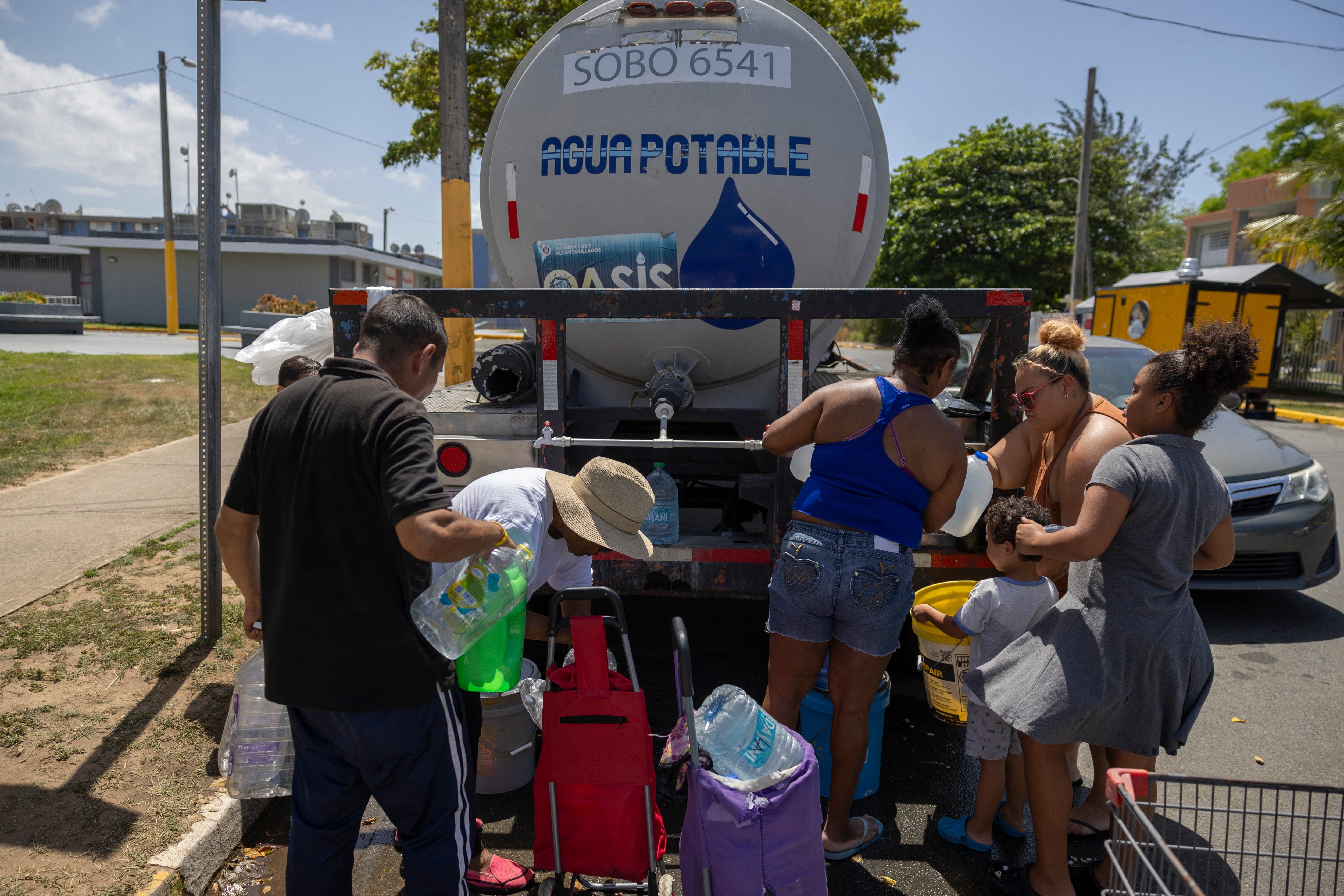 Residents collect drinking water from a tanker truck at an emergency water distribution point