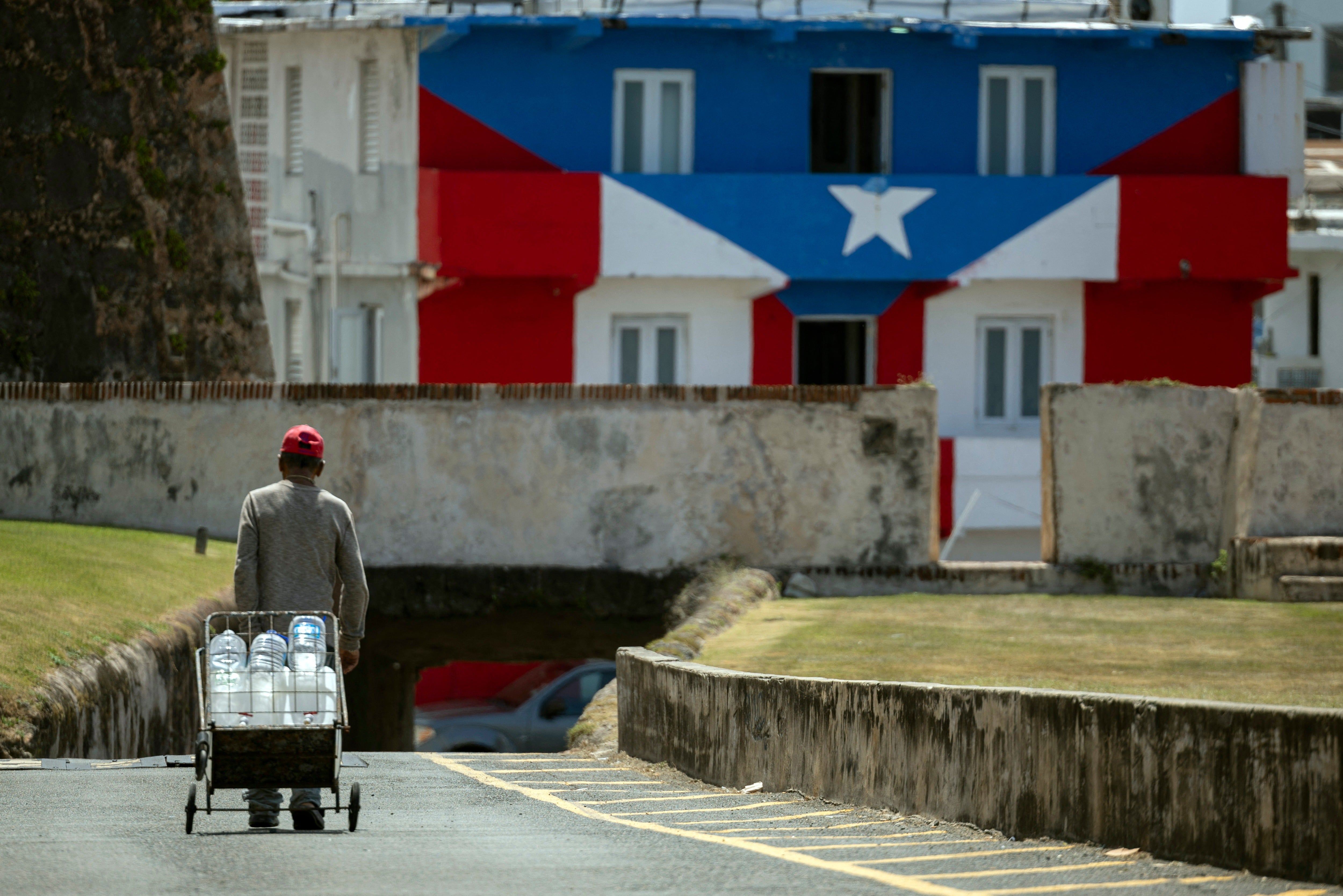 A man transports water containers amid ongoing water shortages in Old San Juan, Puerto Rico
