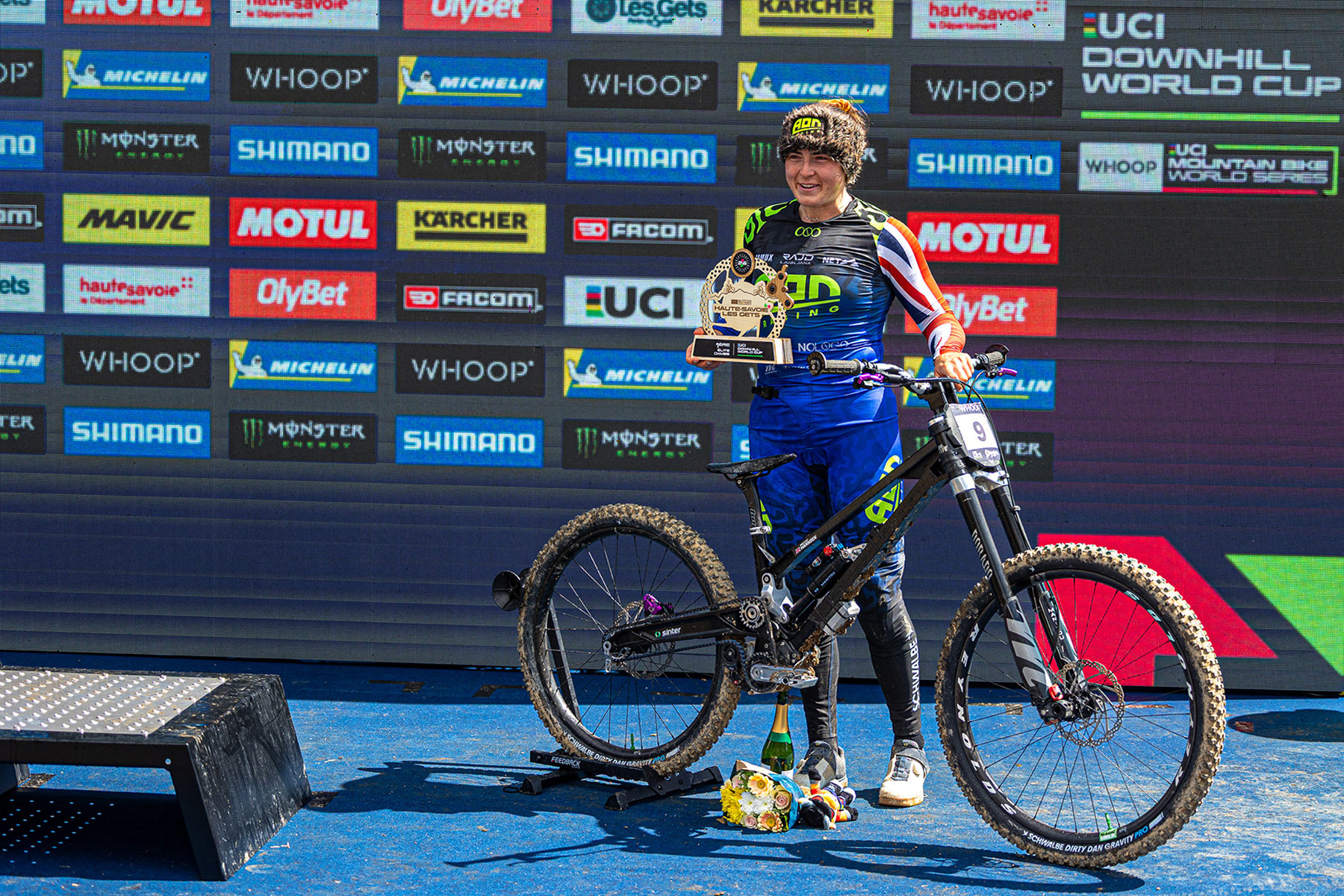 Hattie Harnden takes Gates 100k Belted Purse with 2026 Les Gets DH World Cup win, on stage with her bike