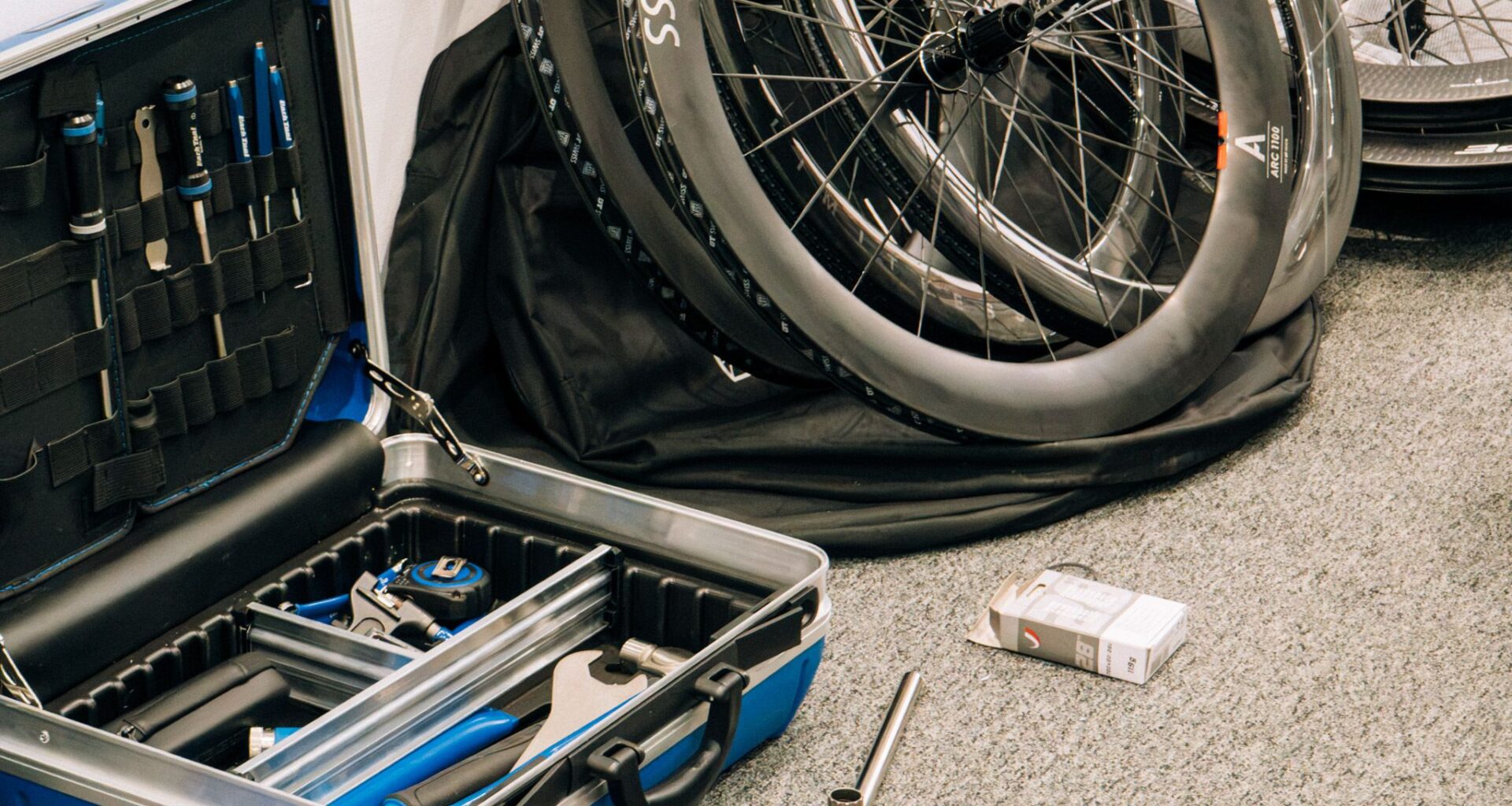 An open toolbox sits next to a pile of road bike wheels