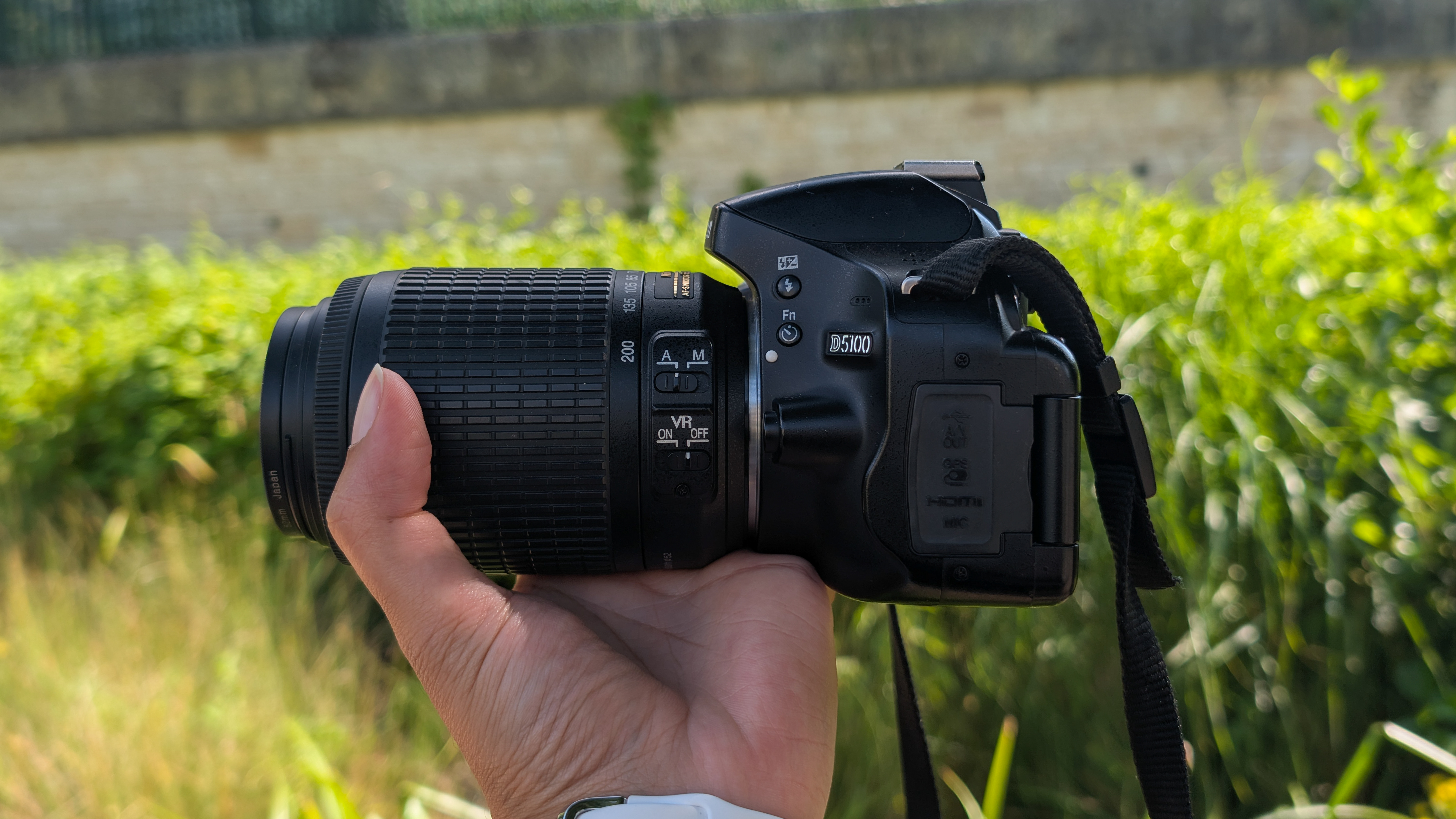 A person holding a Nikon D5100 DSLR camera