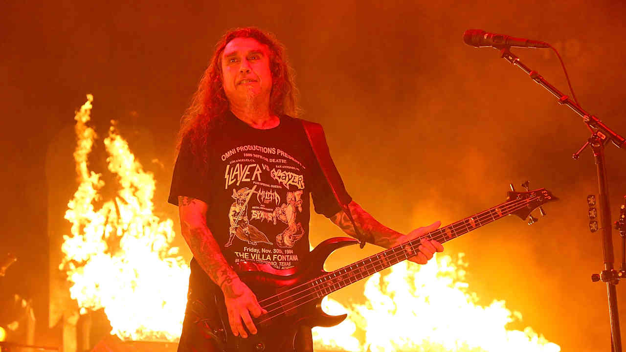 Tom Araya of Slayer onstage wearing a Slayer vs Slayer flyer T-shirt