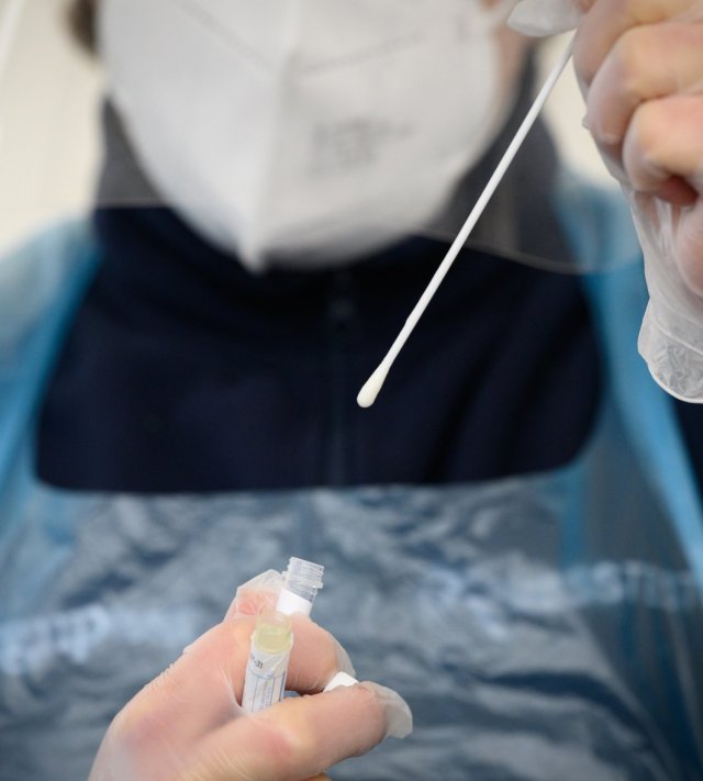A member of the medical team holds up a used swab from a PCR test (Photo: Leon Neal/Getty)