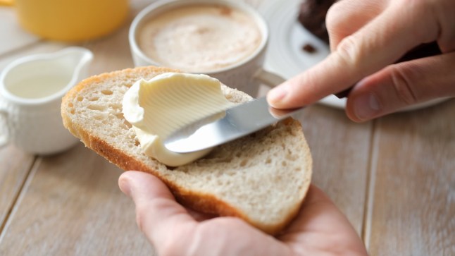 Spreading soft butter on white bread toast, closeup view
