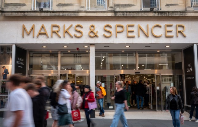 BATH, UNITED KINGDOM - SEPTEMBER 28: Shoppers pass a branch of the high street retailer Marks & Spencer on September 28, 2024 in Bath, England. Founded in 1884, Marks and Spencer Group plc or M&S, is a major British multinational retailer that specialises in selling clothing, beauty, home products and food products. Often seen as quintessentially British and the lynchpin of the British high street with its location normally based at the centre of a retailing district. As retailing habits have changed M&S has recently announced a number of store closures as part of restructuring of the business. (Photo by Matt Cardy/Getty Images)