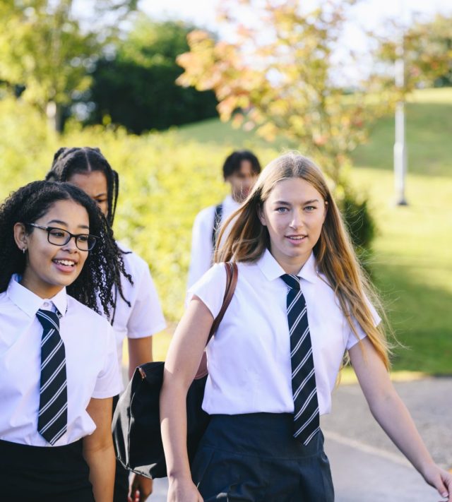 Two high school friends, one wearing glasses, on way to school with contented expressions