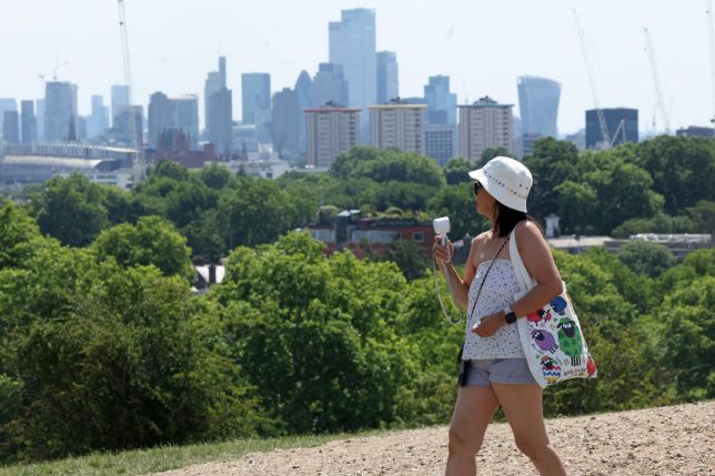 A person uses a hand-held fan to keep cool on Primrose Hill in central London on June 27, 2026, during a heatwave. The UK broke the record for a June temperature for the third day in a row on Friday, the Met Office weather agency said, as a sweltering heatwave strained schools and hospitals and drove down business. A provisional 37.3 C record temperature was chalked up in Santon Downham, a village in Suffolk. (Photo by Toby Shepheard / AFP via Getty Images)