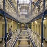 Two prisoners stand outside their cell on the A wing at Wandsworth prison. The main prison has 5 wings (A to E) each with 4 landings; A wing holds Long term prisoners and is fitted with suicide netting between each floor. HMP Wandsworth in South West London was built in 1851 and is one of the largest prisons in Western Europe. It has a capacity of 1456 prisoners. (Photo by Andrew Aitchison/In Pictures Ltd./Corbis via Getty Images)