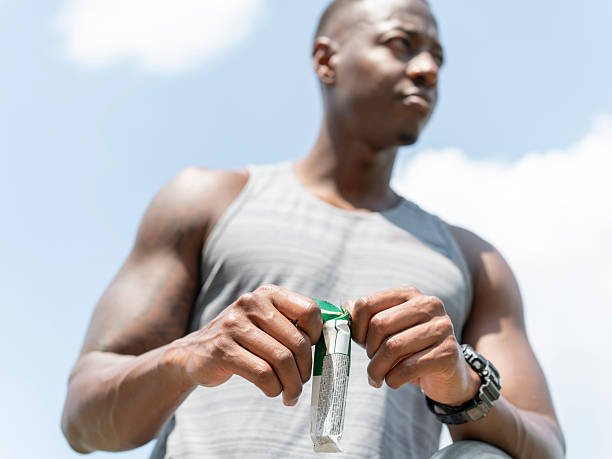 Man opening protein bar during workout