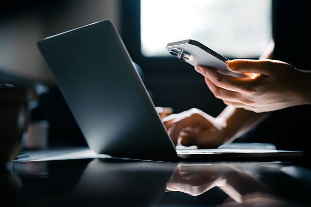Close-up shot of a woman using mobile device with Two-Factor Authentication (2FA) security while logging in securely to her laptop. Privacy protection, internet and mobile security