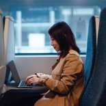 Young woman using laptop on public transport. Business travel. Business and technology concept.