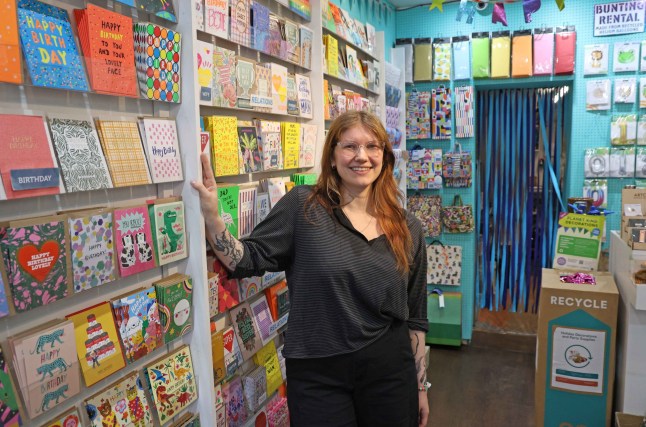 Hannah Sharmain standing in a shop filled with greetings cards.
