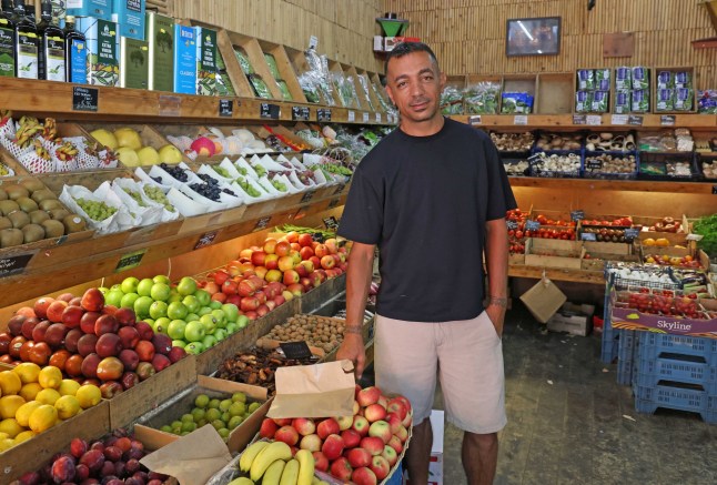 Deniz Bilgin stands in a fruit and veg shop on Stoke Newington Church Street. (Credit: Nigel Howard/Vox Pop)