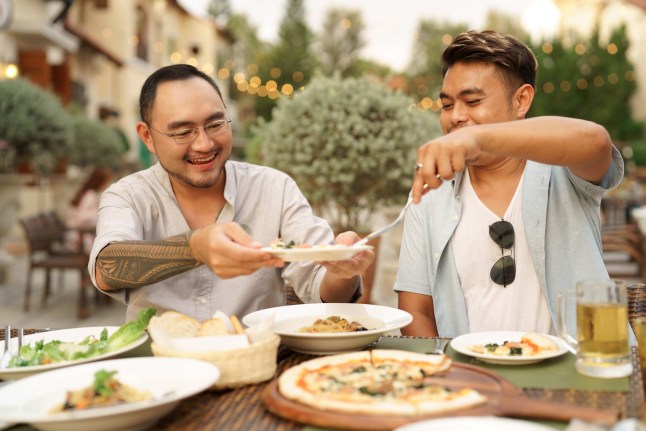 A man taking care boyfriend serving meals while dining at restaurant