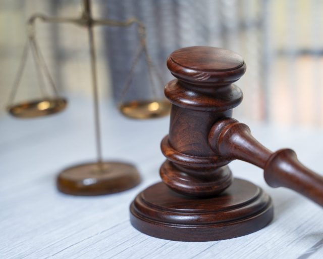 Justice hammer or gravel on a table and justice scale at the background, concept image