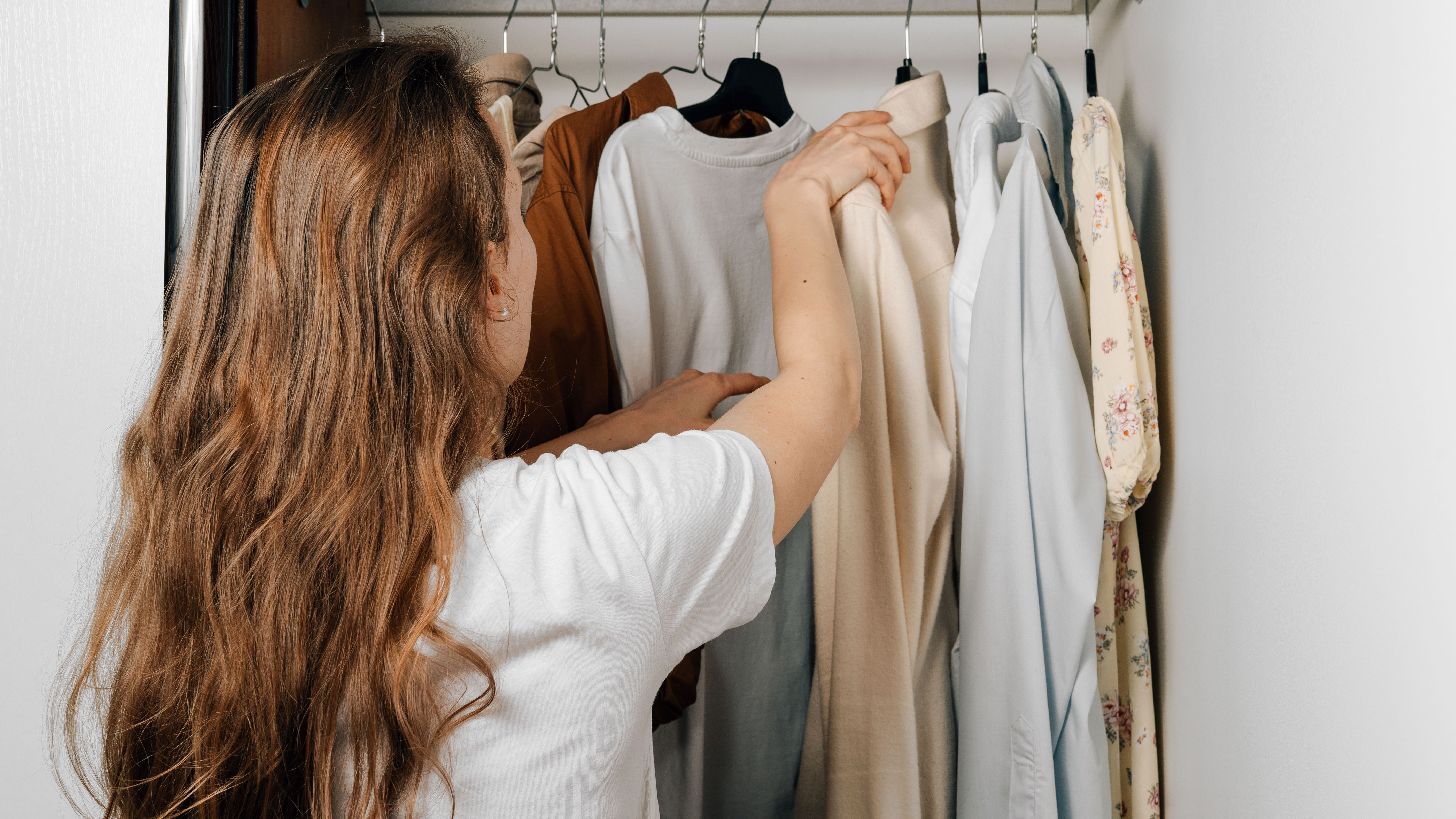 Woman looking in a wardrobe of clothes.