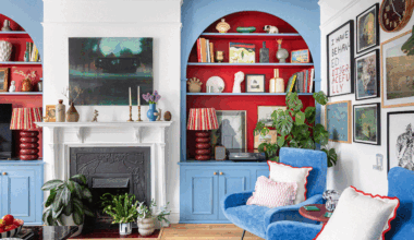 a living room with bright blue painted alcove shelving with bold contrasting red recessed shelves with a gallery wall, fireplace and plenty of colour
