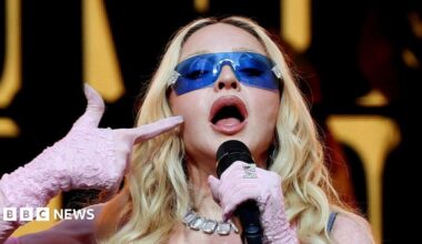Madonna, wearing purple sunglasses and pink gloves, performing during a surprise concert in Times Square in New York City in June