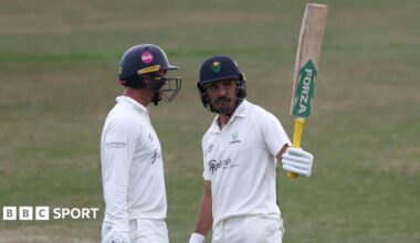 Glamorgan batter Kiran Carlson raises his bat stood next to Colin Ingram having scored 50 against Leicestershire