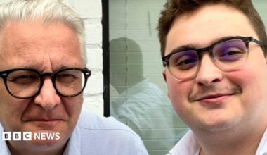 A close-up of two men both wearing glasses