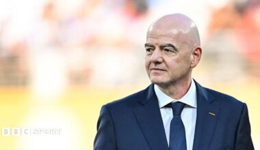 Gianni Infantino, wearing a dark suit and tie, looks to his right