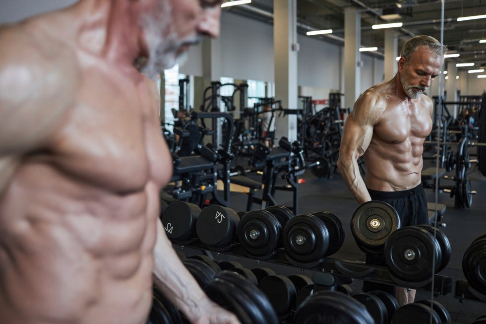 Mature man choosing dumbbell in gym mature man choosing dumbbell in gym