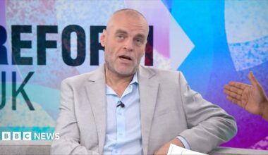 Tim Montgomerie, with short cropped hair and a grey beard, is wearing an open necked shirt and suit jacket. He is in the Newsnight studio
