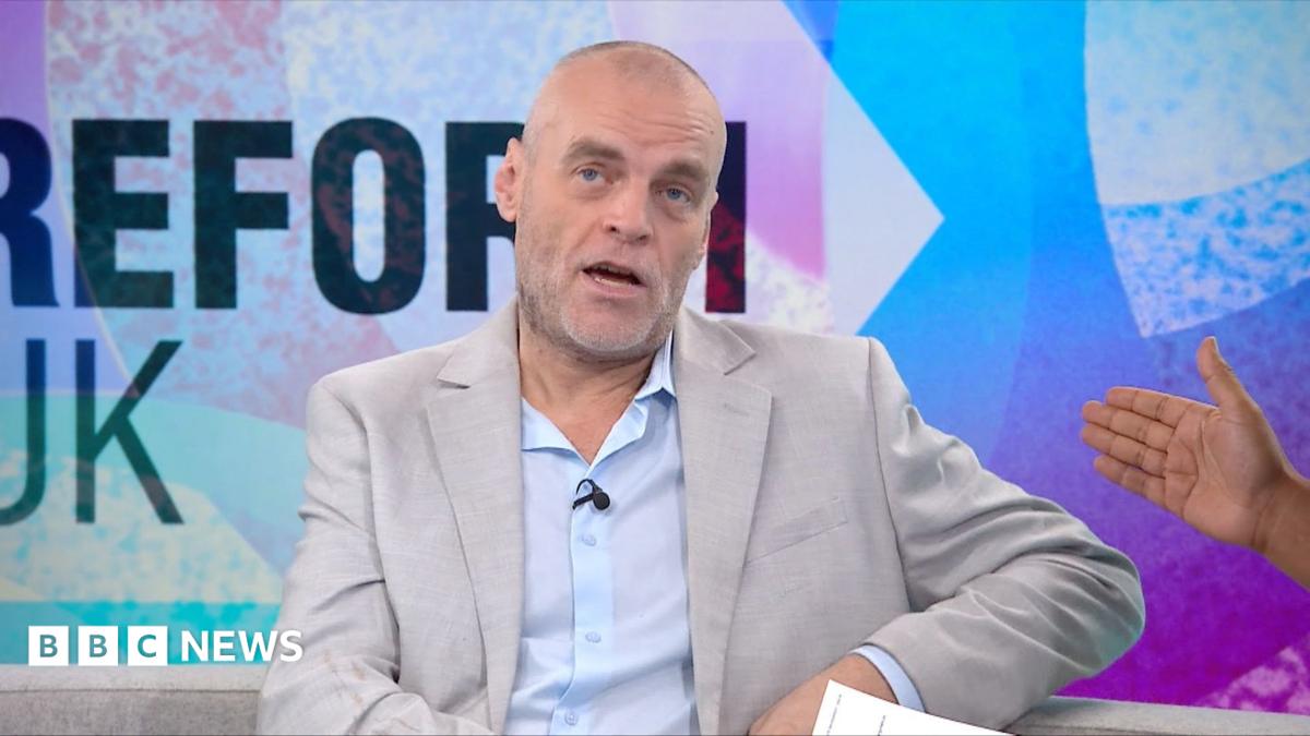 Tim Montgomerie, with short cropped hair and a grey beard, is wearing an open necked shirt and suit jacket. He is in the Newsnight studio