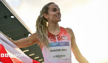 Georgia Hunter Bell smiles while unfurling an England flag