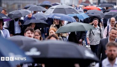 A busy scene of people walking in the rain with umbrellas up.