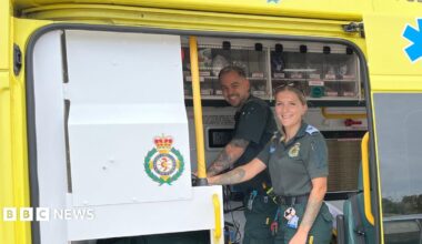 Paramedics Lee and Sophie smile at the camera as they stand inside the back of the ambulance.
