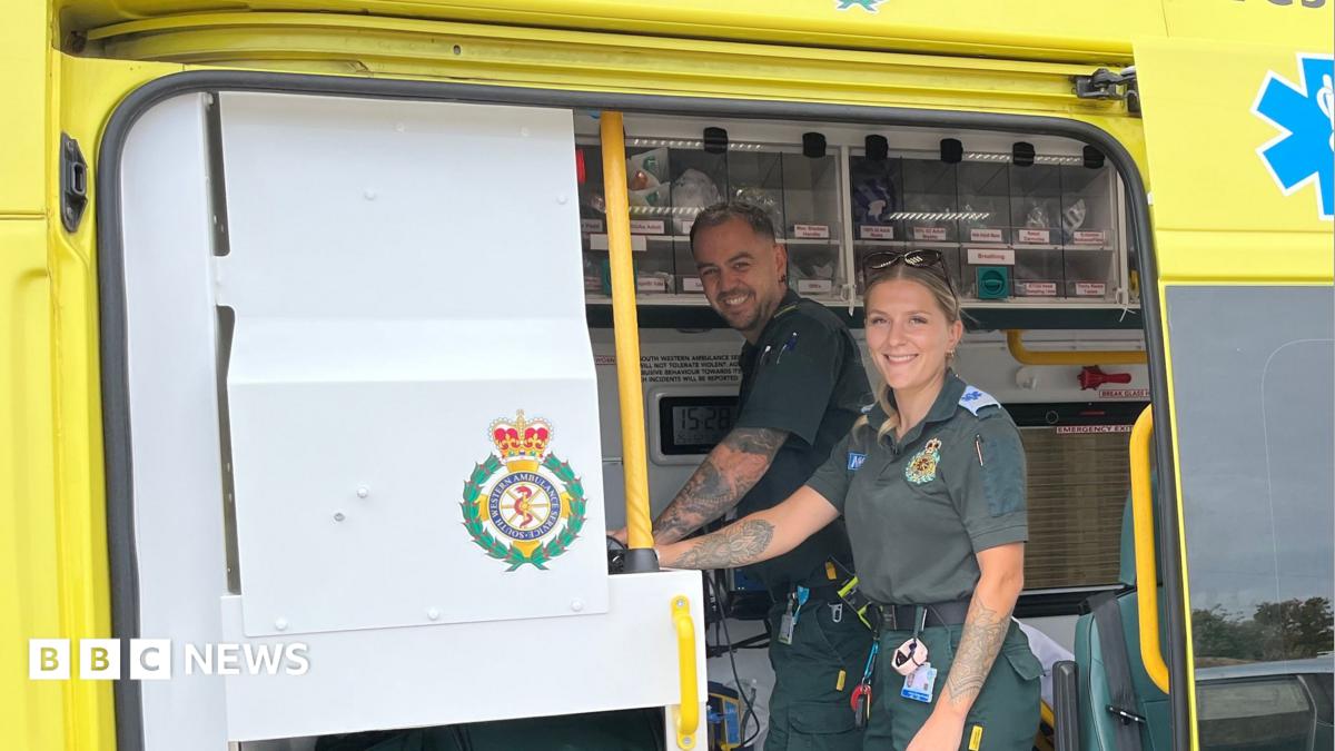 Paramedics Lee and Sophie smile at the camera as they stand inside the back of the ambulance.
