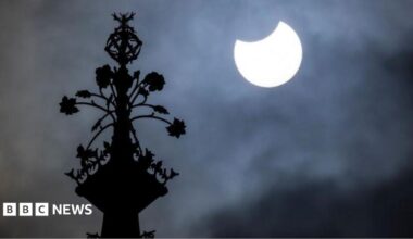 People watch the sky from Primrose Hill in north London as photographers aim cameras towards the horizon.