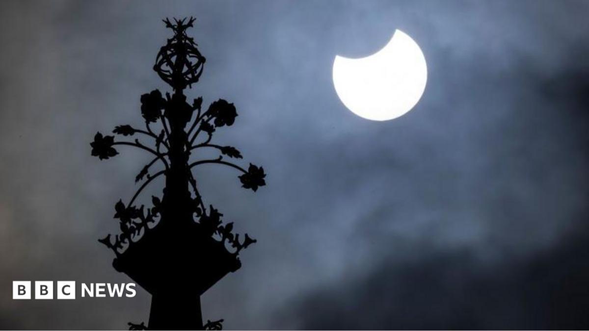 People watch the sky from Primrose Hill in north London as photographers aim cameras towards the horizon.