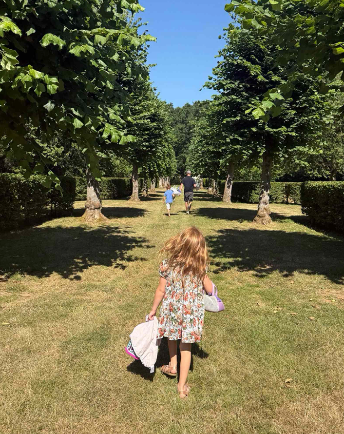 Prince Harry and Prince Archie walk through the grounds of Althorp House carrying bouquets of flowers, with Princess Lilibet following behind during the family's emotional visit.
