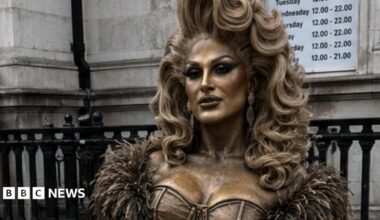 An AI image of the proposed life-size statue of The Vivienne on a concrete bench at the entrance to Liverpool's officially recognised Pride Quarter