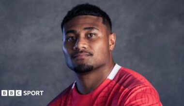 A portrait photo of Sam Moli in a red Tonga rugby jersey.