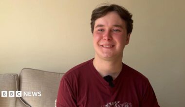 Nineteen-year-old Dmytro. He is wearing a red t-shirt and is sitting on a sofa.