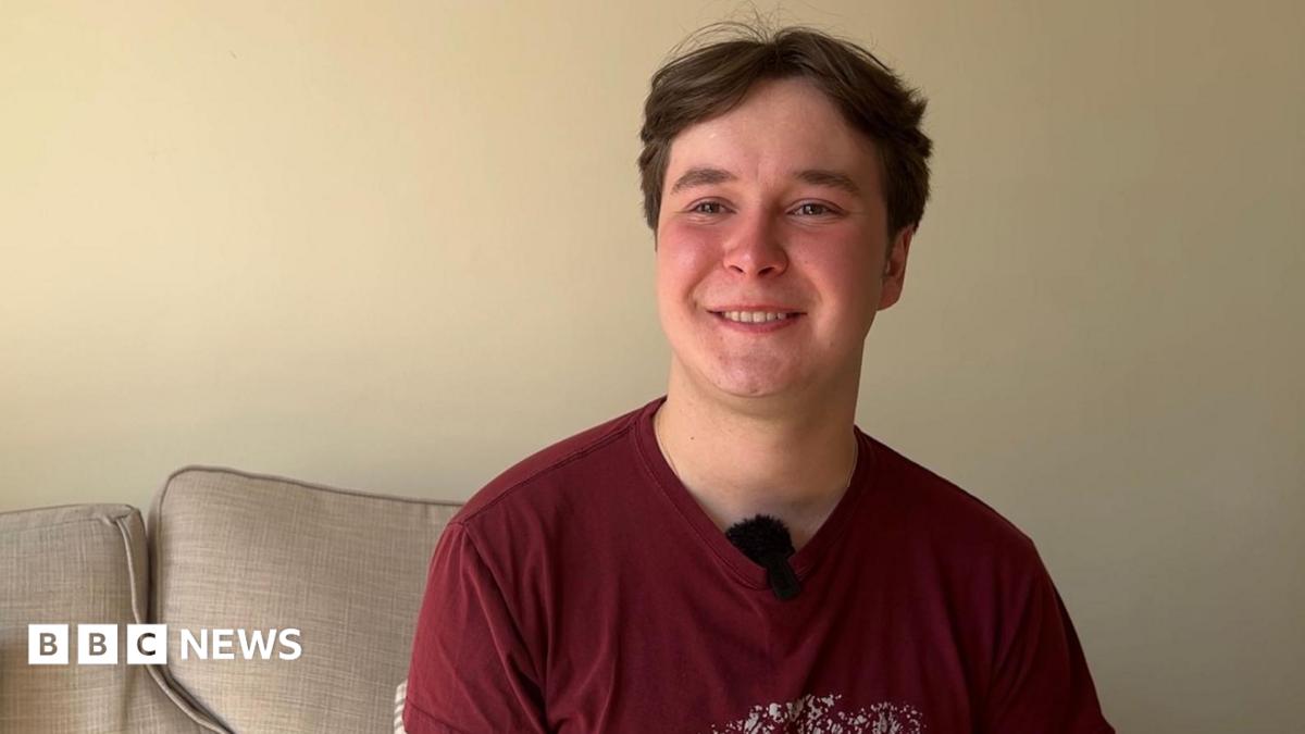 Nineteen-year-old Dmytro. He is wearing a red t-shirt and is sitting on a sofa.