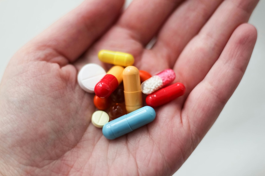 A woman's open palm holds a mix of different tablets.