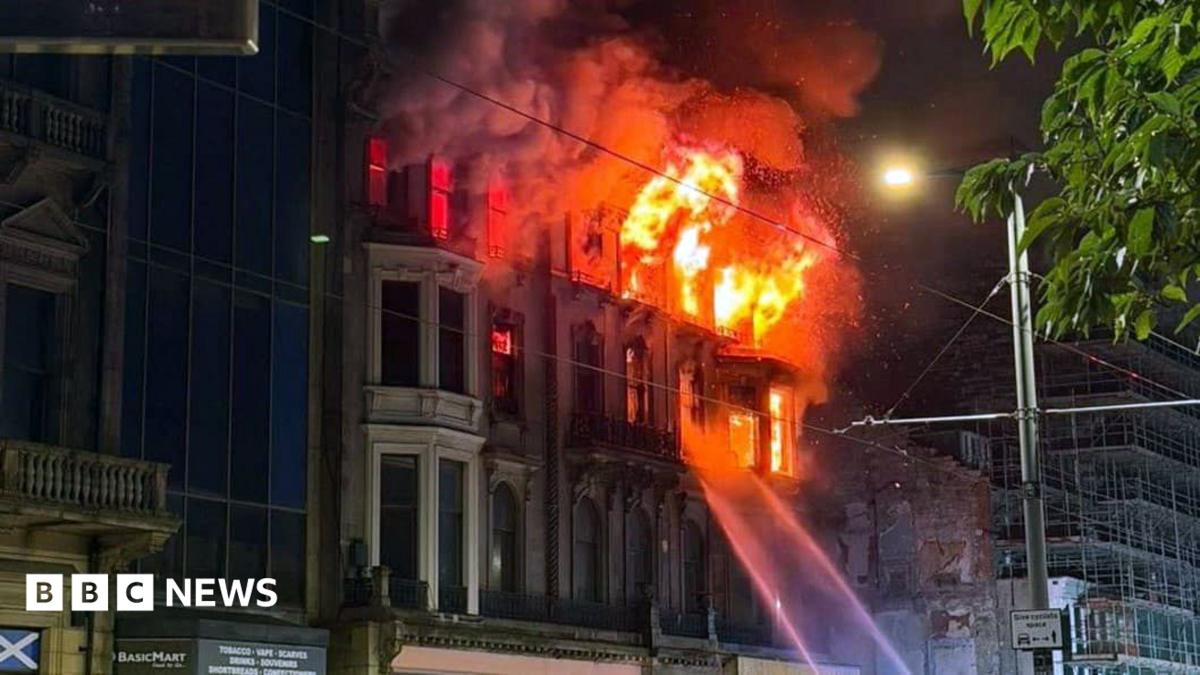 An old Victorian building on fire with jets of water directed at the flames. The photo is taken at night.