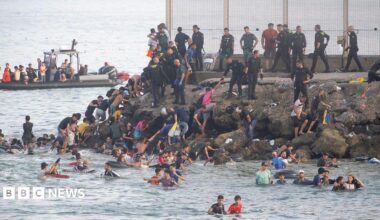 Dozens of migrants walking on a coastal path