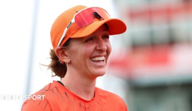Kate Cross smiles, while wearing orange Sunrisers Leeds kit