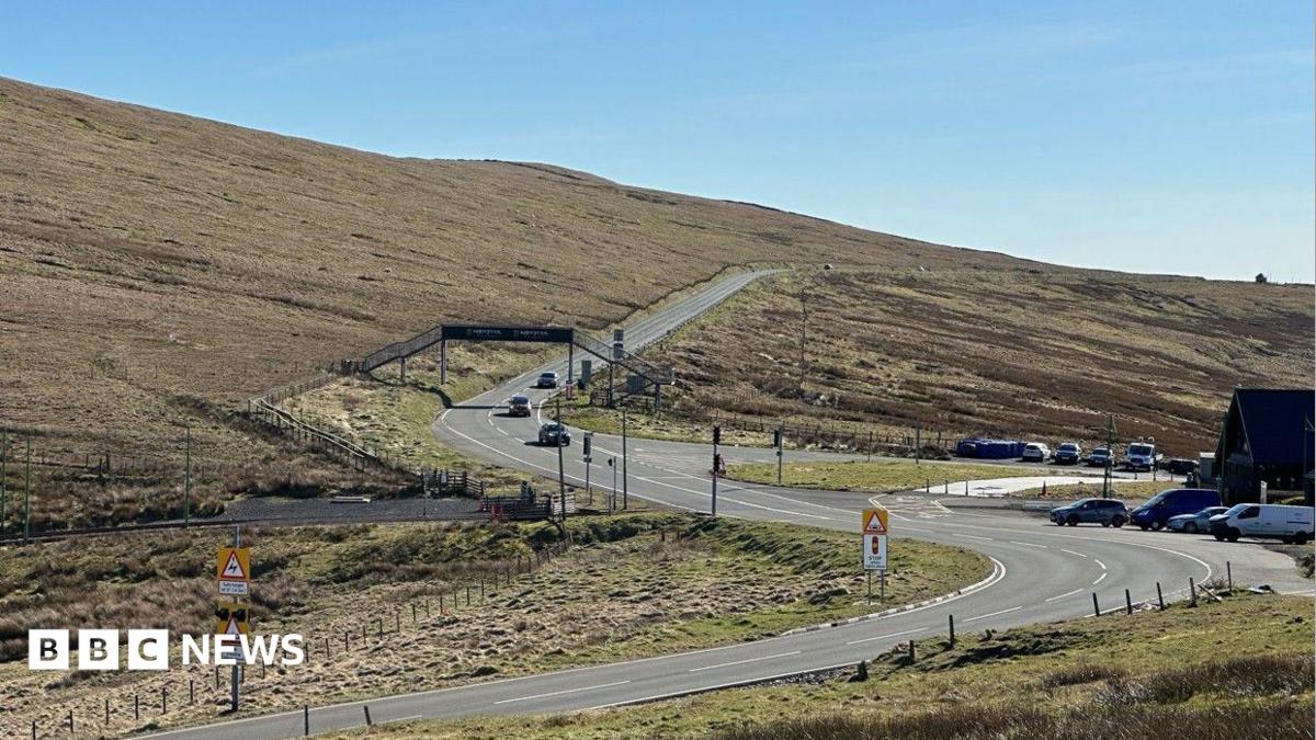 The Mountain Road at the Bungalow with the road snaking into the distance under a metal footbridge.