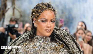 Rihanna has an elaborate, curly gold head dress on, and a silver bejewelled dress on the Met Gala red carpet.