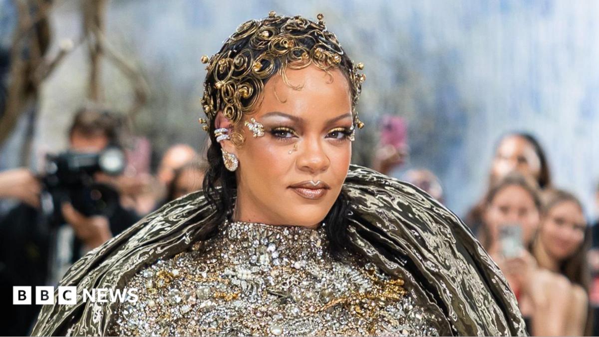 Rihanna has an elaborate, curly gold head dress on, and a silver bejewelled dress on the Met Gala red carpet.